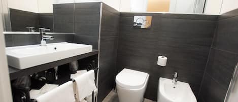 A modern bathroom with a large sink, bidet, and separate toilet.