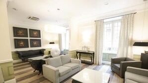 Un salón espacioso con sofá, sillones, una mesita de centro, chimenea y un amplio ventanal con cortinas.
