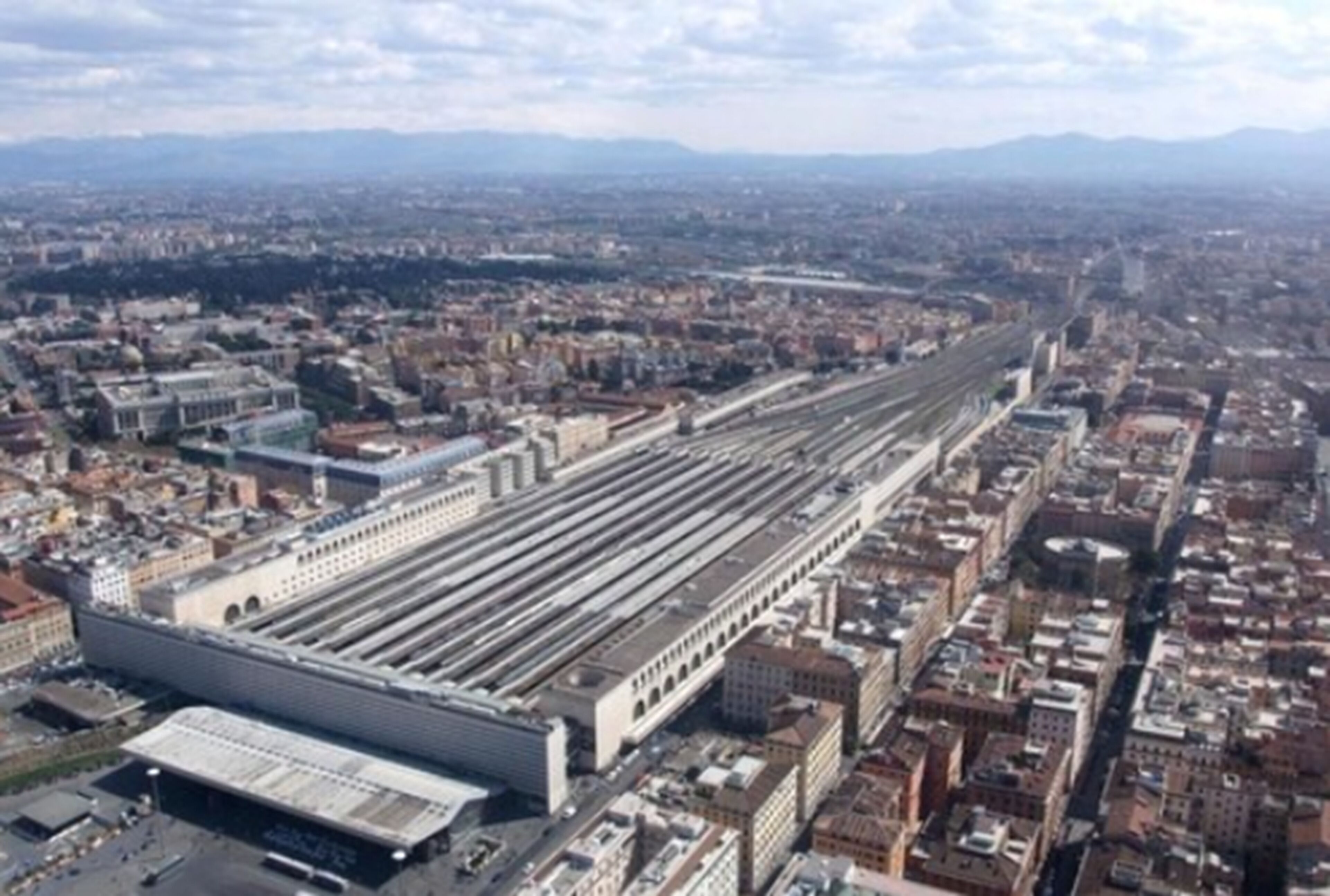 A large train station with multiple tracks and a prominent building with a flat roof.