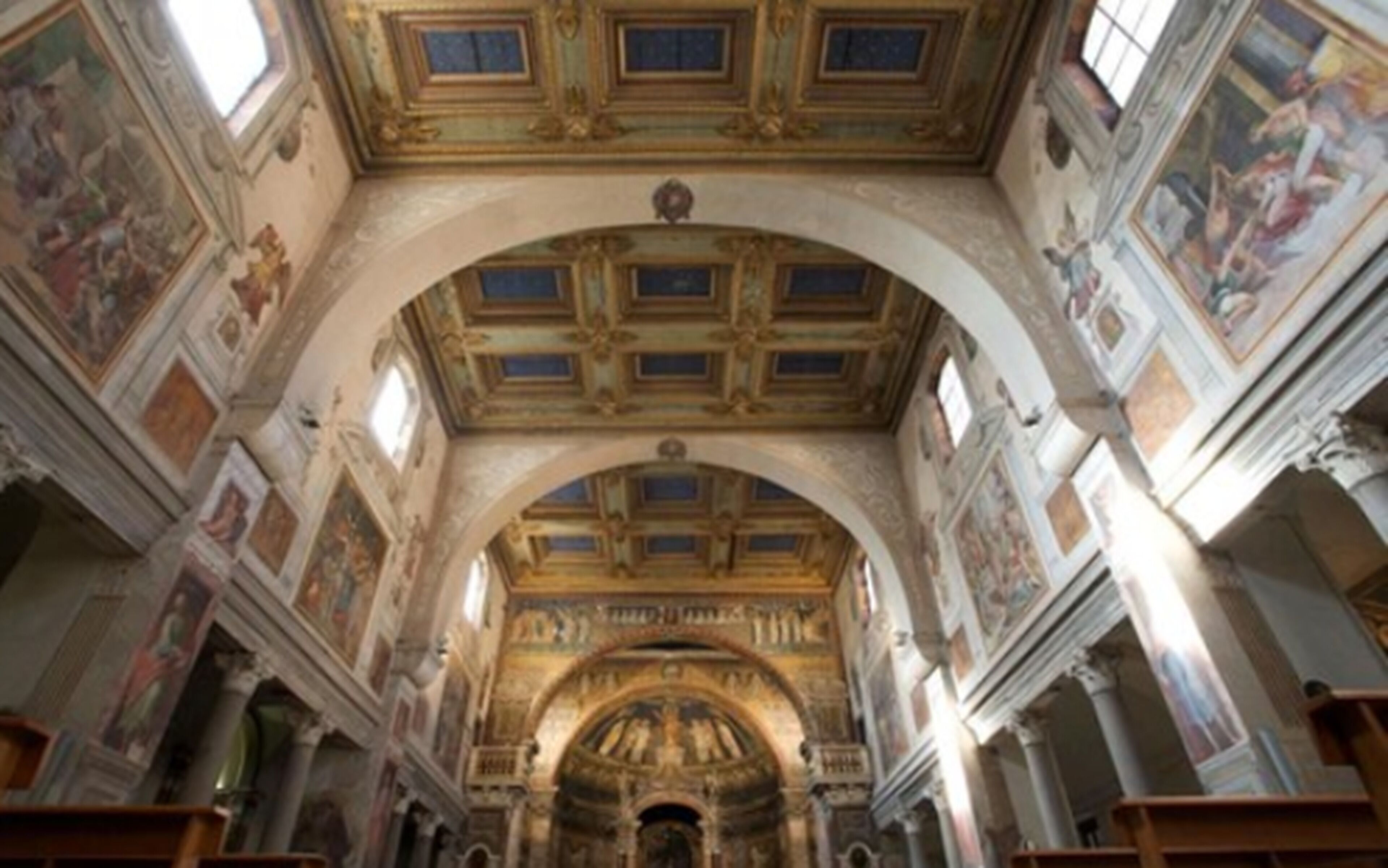 An interior with a high arched ceiling, frescoes, and classical architectural elements.