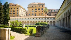 Un patio con un edificio de varios pisos y una serie de arcos a lo largo de un lado.