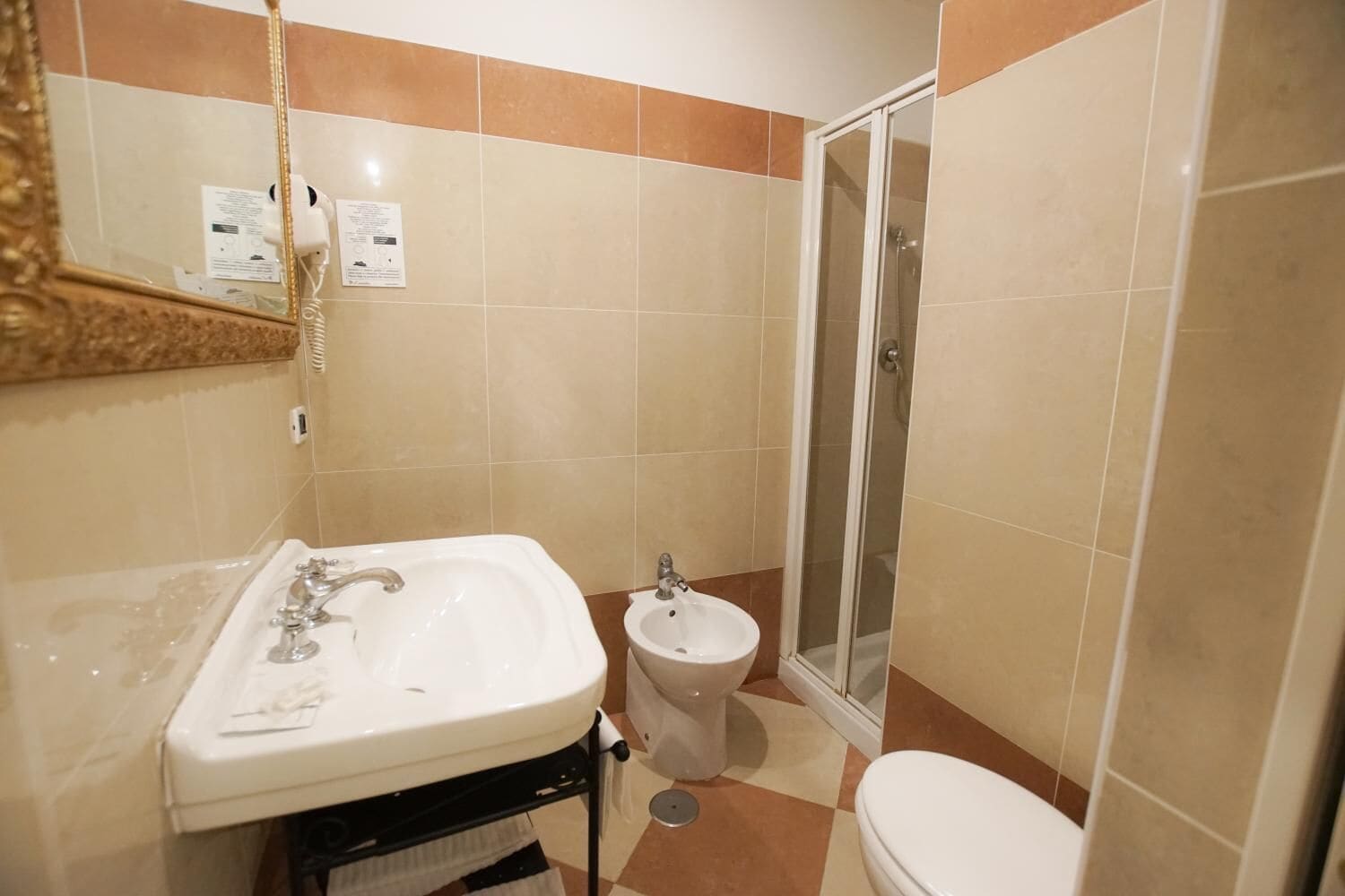 A bathroom with a sink, bidet, toilet, and a glass-enclosed shower.