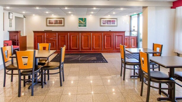Ein Hotel-Speisebereich mit mehreren Tischen und Stühlen, einer Rezeption und einem Logo an der Wand.