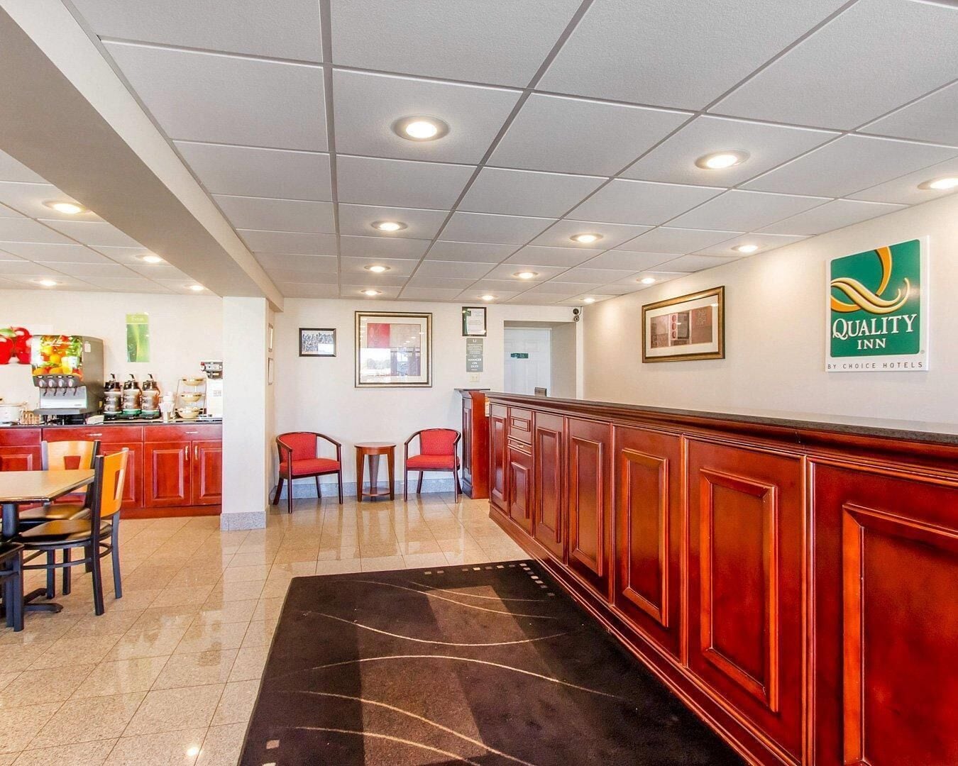 A hotel lobby with a reception desk, seating area, and a coffee machine.