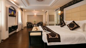 A hotel room with a large bed, a TV mounted on the wall, a small table with a vase, and two chairs. - Hanoi Emotion Hotel (Hanoi)