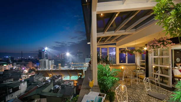 A rooftop terrace with seating, a magazine, and a view of the city skyline at night. - Hanoi Emotion Hotel (Hanoi)