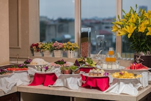 A buffet table with various dishes, including salads, fruits, and desserts, set up with white and red tablecloths. - Hanoi Emotion Hotel (Hanoi)