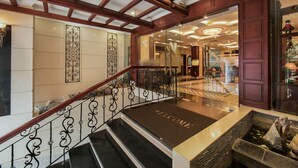 A grand staircase with a 'WELCOME' mat leading to a lobby area with a chandelier and a view of the interior. - Hanoi Emotion Hotel (Hanoi)