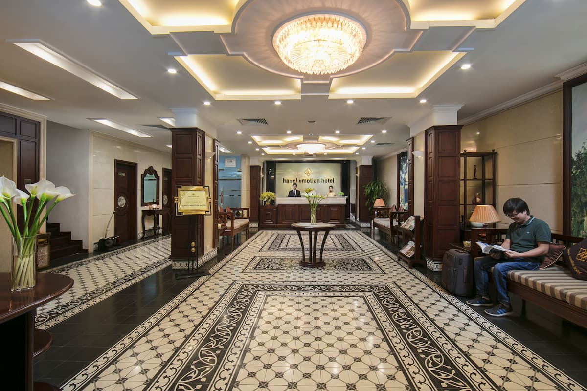 Un hall d’hôtel agrémenté d’un lustre, d’un comptoir d’accueil, d’un espace salon et d’un sol à motifs.
