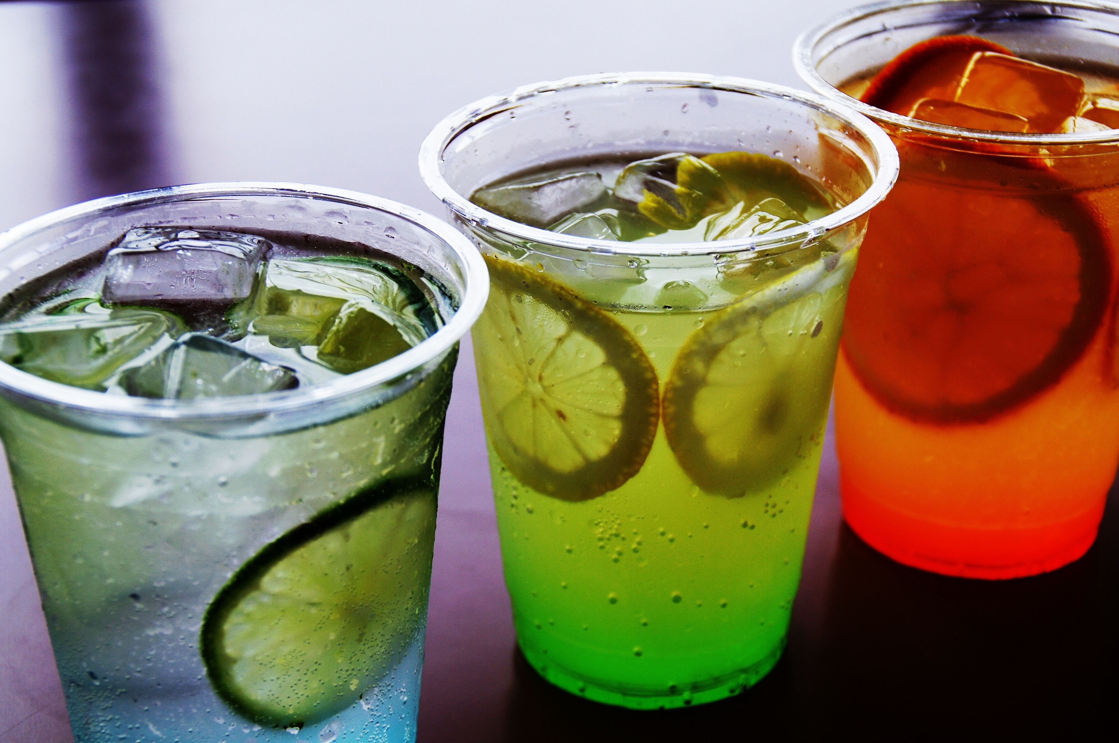 Tre glas med iskalla drycker, isbitar och limeskivor.