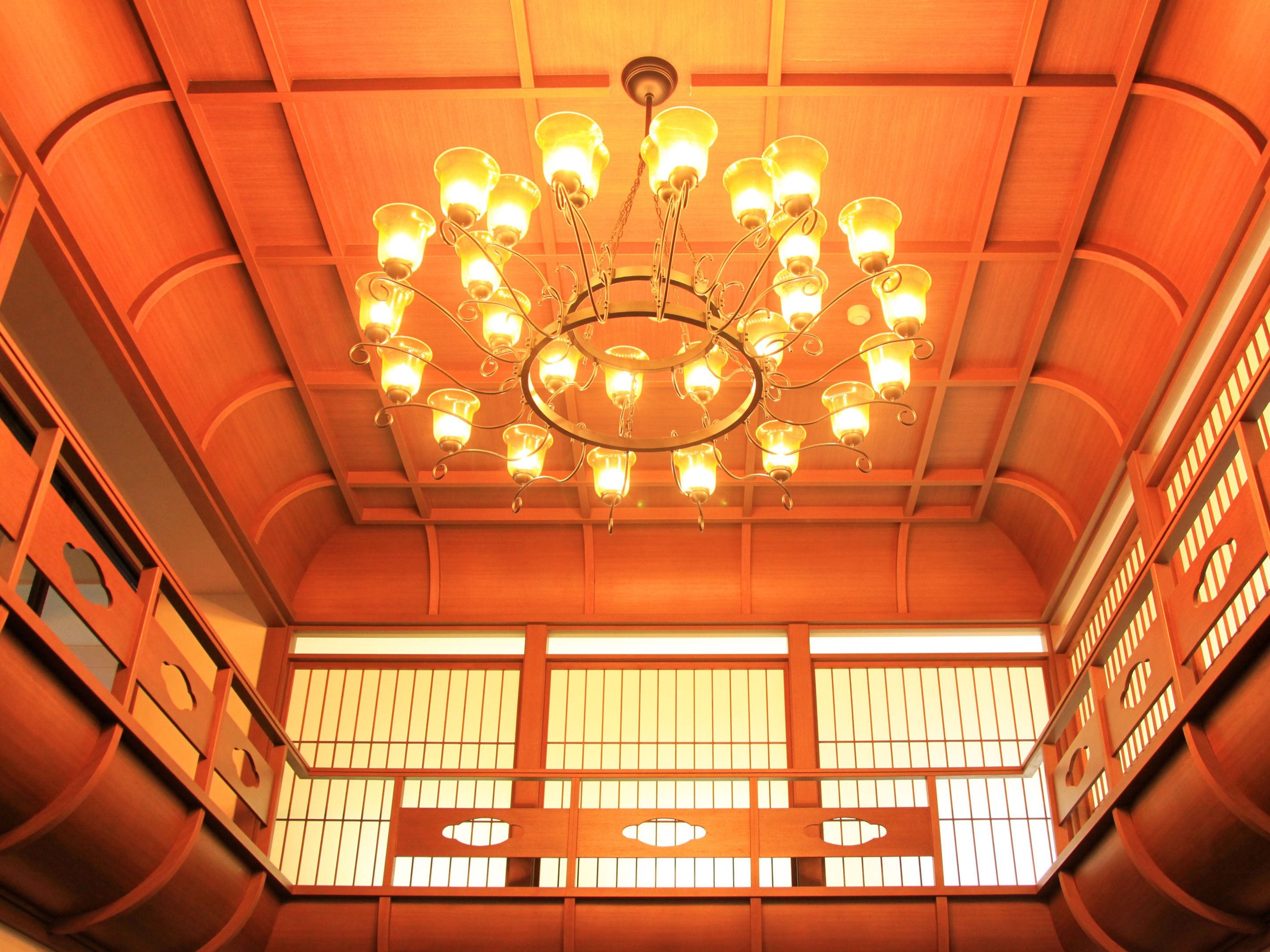 Un intérieur japonais traditionnel avec un plafond en bois, un lustre circulaire et des paravents shoji.