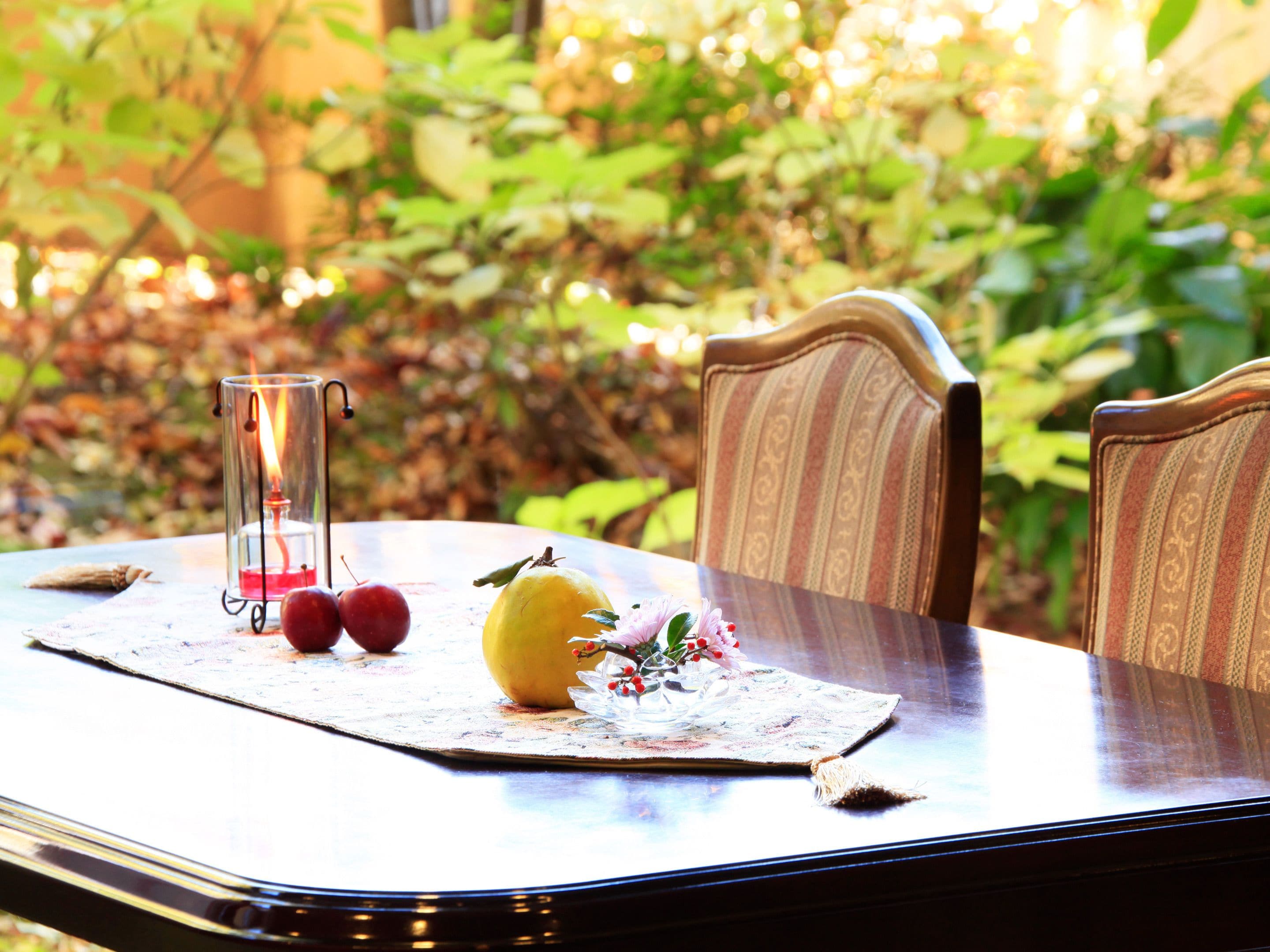 A table with a placemat, a candle, and fruit.