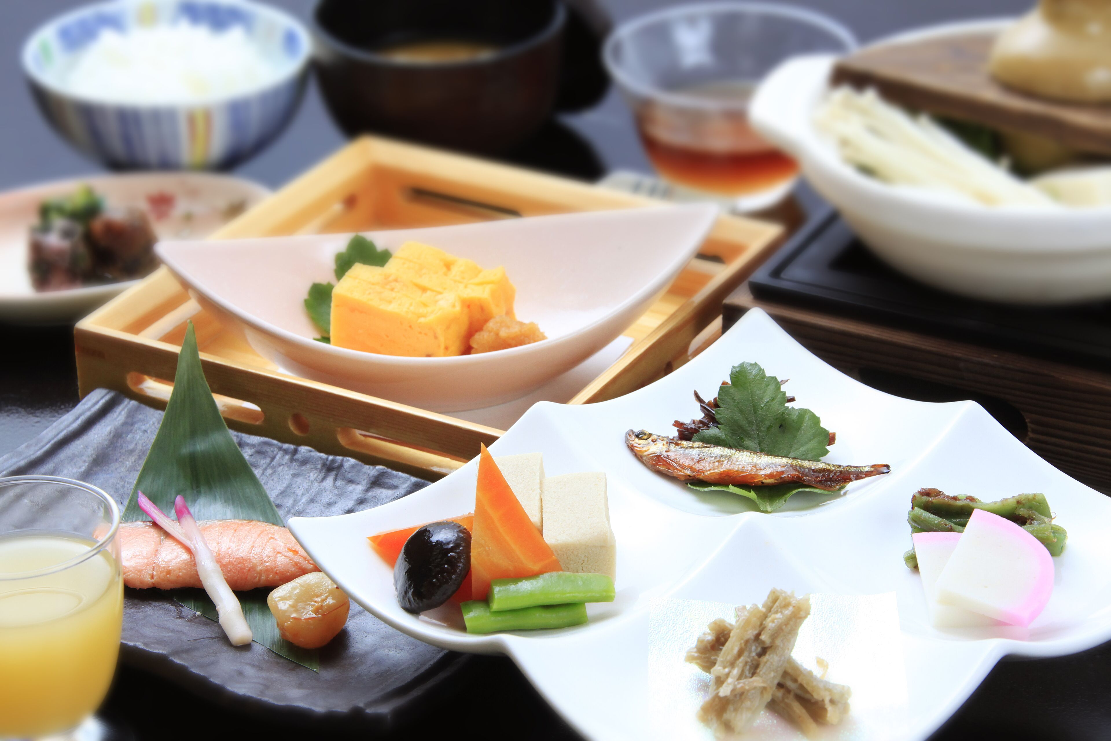 A variety of dishes on a table, including sushi, sashimi, and pickled vegetables.