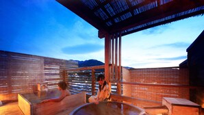 A hot spring bath area with wooden benches and a large central hot tub.