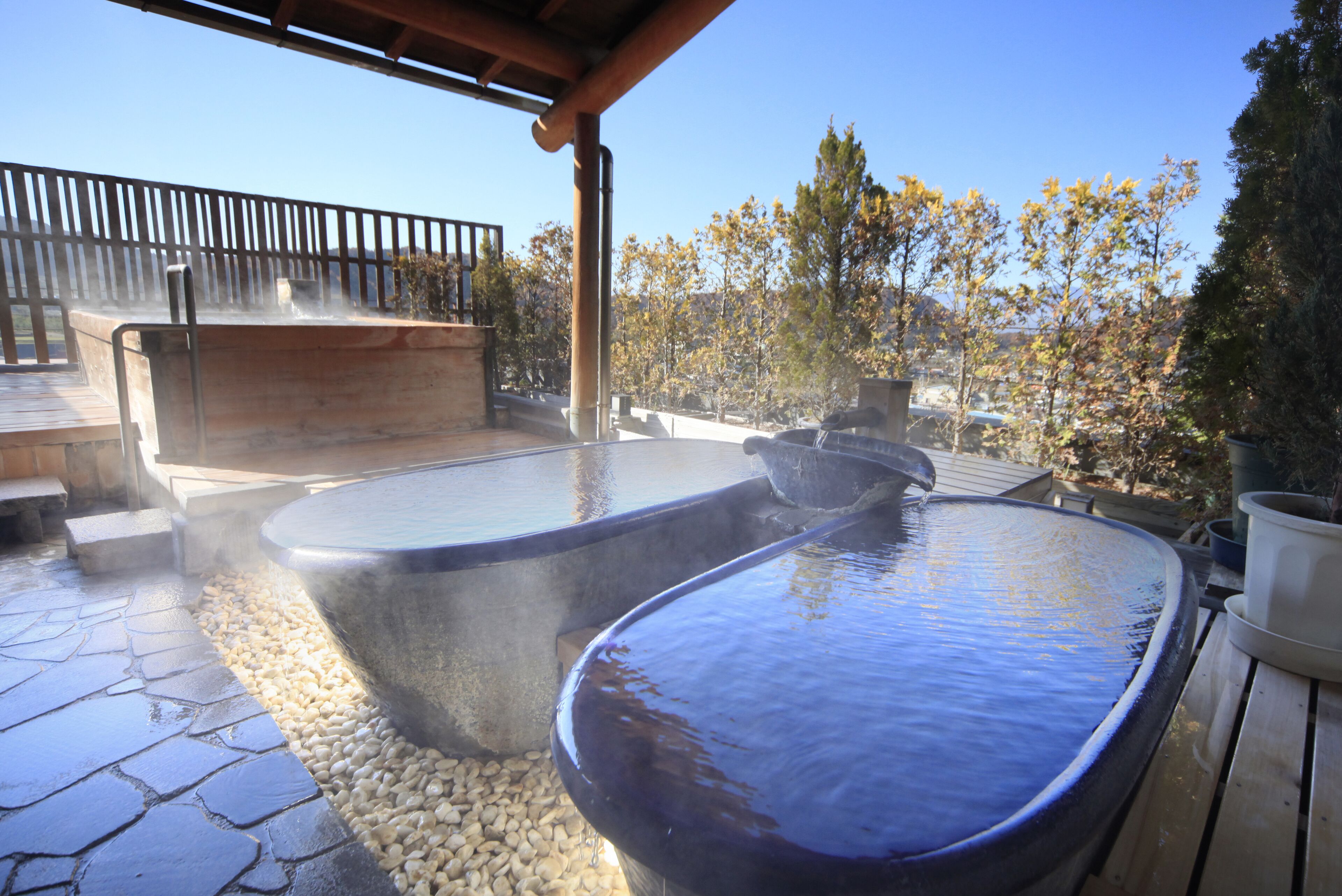 A hot tub area with stone flooring and a wooden deck.