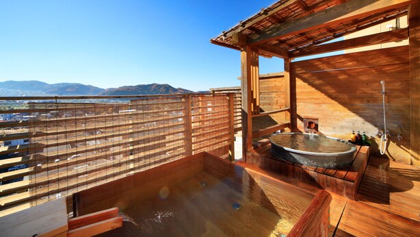 A wooden spa with a hot tub and a view of mountains.