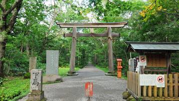 A traditional Japanese torii gate at the entrance of a forested area.