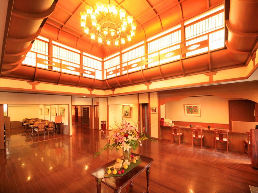 Un vaste hall doté d’un plancher en bois, d’un lustre et de fenêtres de style japonais traditionnel.