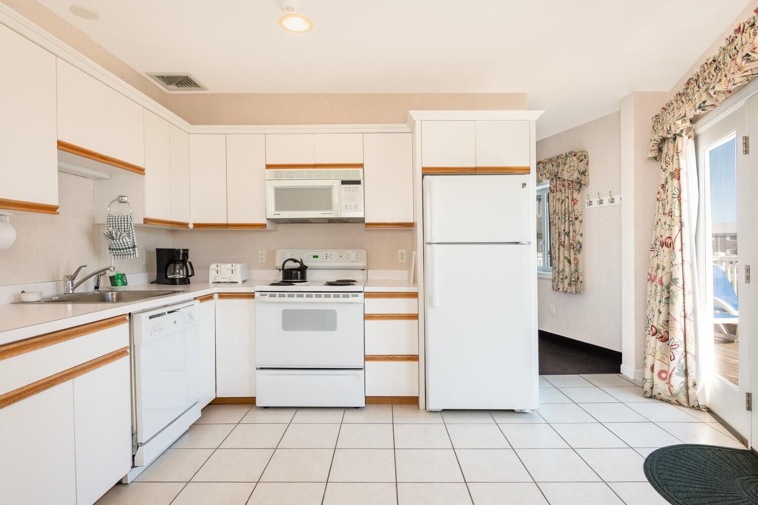 A compact kitchen with white cabinets, a microwave, a stove, and a refrigerator.