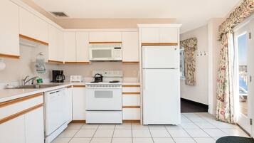A compact kitchen with white cabinets, a microwave, a stove, and a refrigerator.