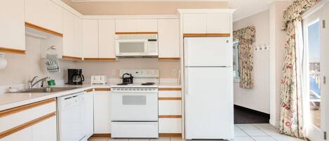 A compact kitchen with white cabinets, a microwave, a stove, and a refrigerator.