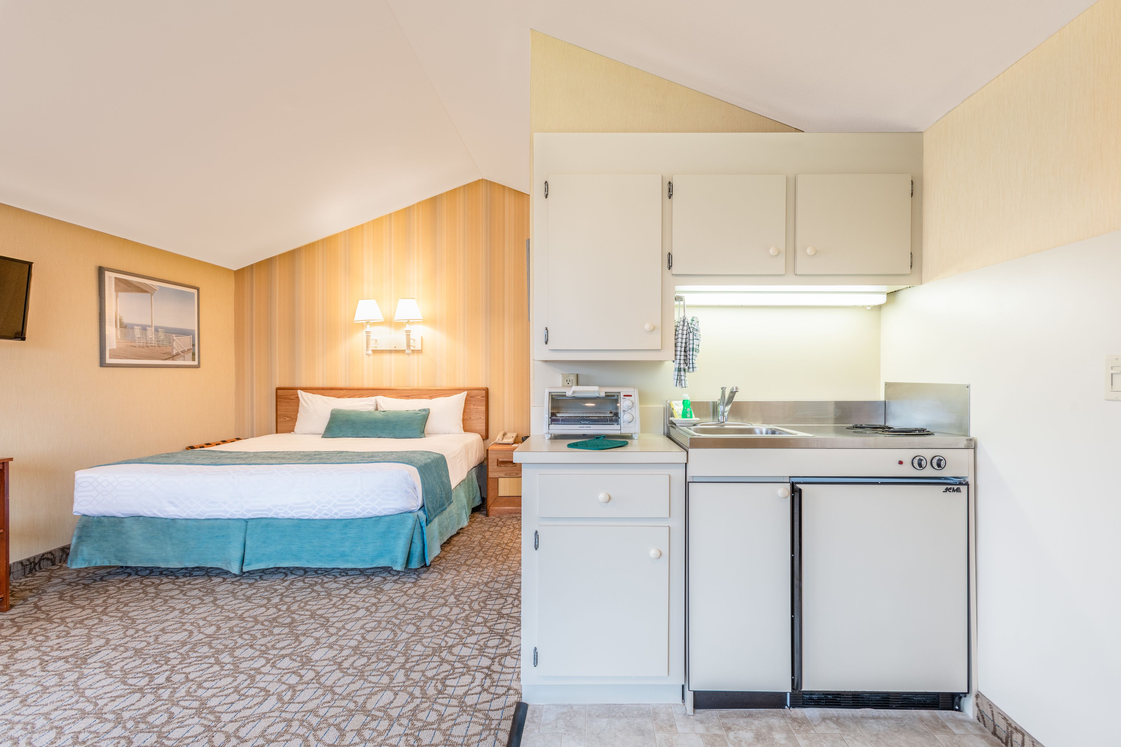 Une chambre d’hôtel avec un lit, une petite kitchenette et une salle de bain.