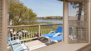 Ein Balkon mit blauen Lounge-Stühlen und einer Holzterrasse mit Blick auf einen See.