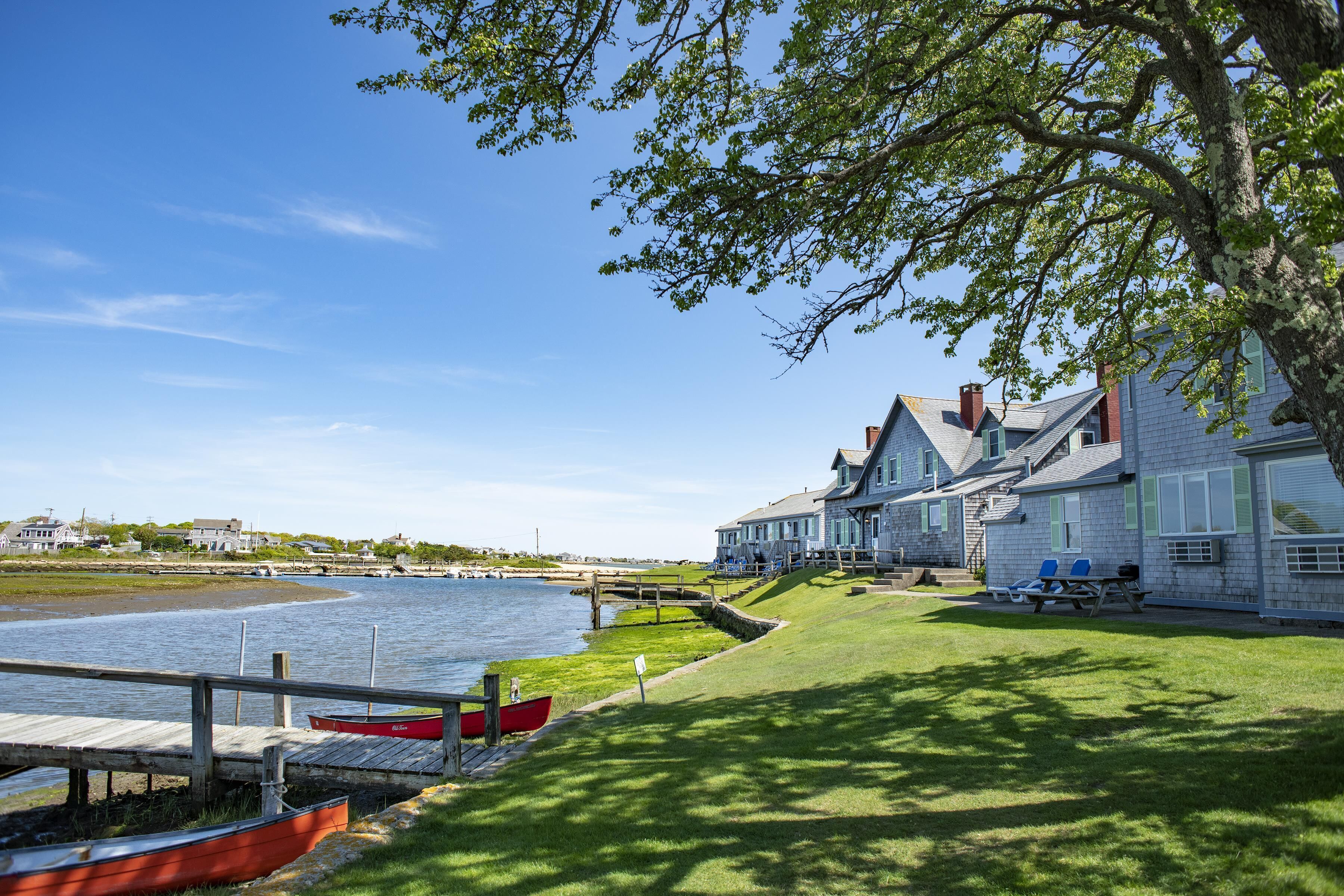 A waterfront property with a dock, a red boat, and a grassy area with a picnic table.
