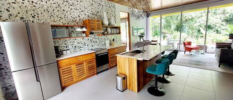 A modern kitchen with a central island, wooden cabinets, and a built-in microwave.