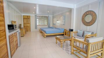 A spacious room with a large bed, a wooden desk, a chair, and a sofa.