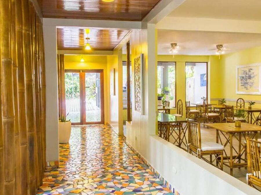 Un restaurant amb un sòl de mosaic colorit, sostre de fusta i parets grogues.
