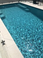 Una piscina al aire libre, sillones reclinables de piscina