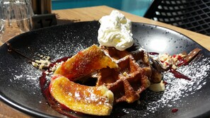 Ein Dessertteller mit Waffeln, Schlagsahne und Früchten.