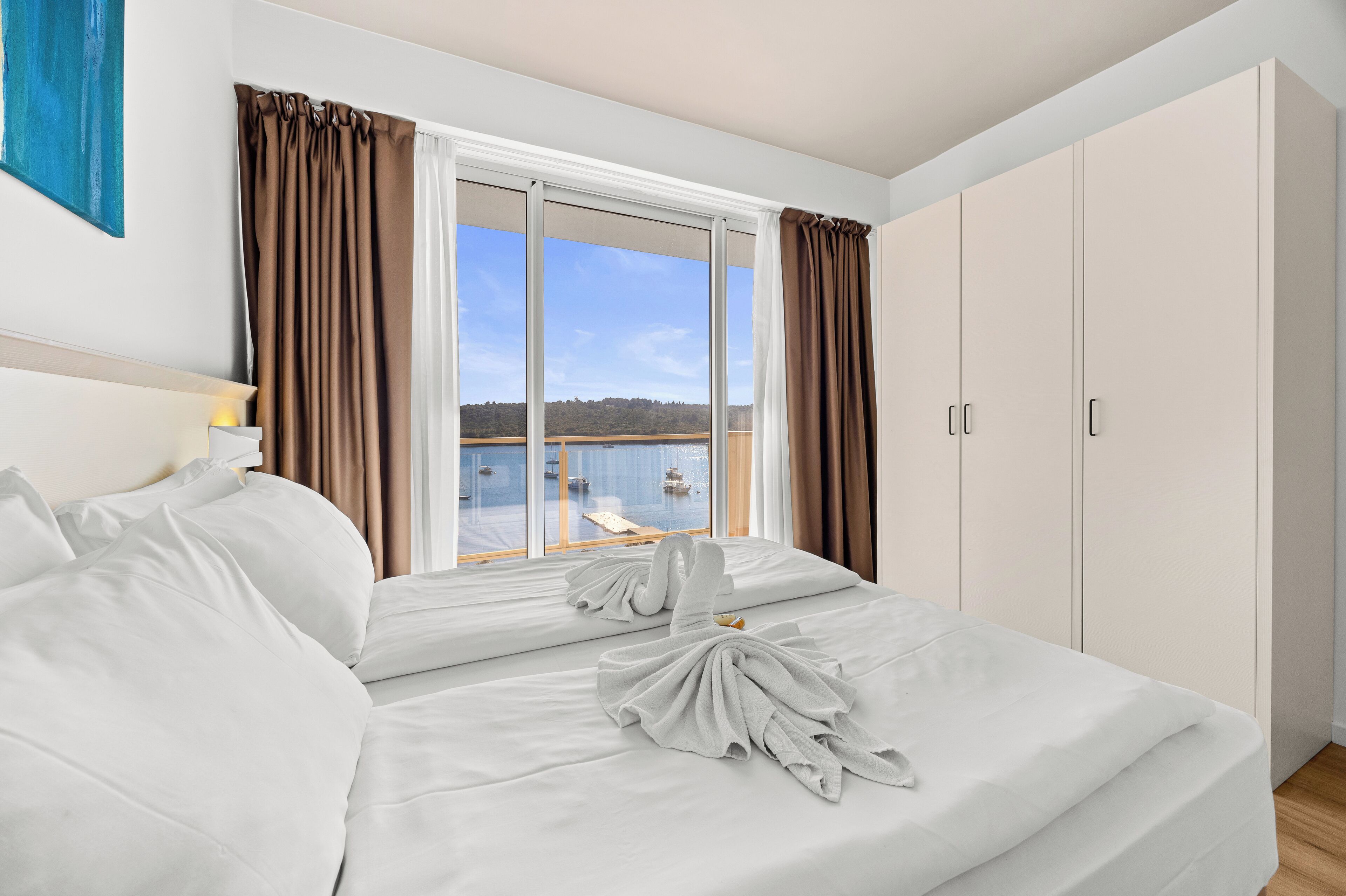 Ein Hotelzimmer mit einem großen Bett, Meerblick und einem Balkon.