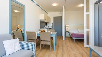 Quarto compacto com área de refeições, uma cama e cozinha compacta.