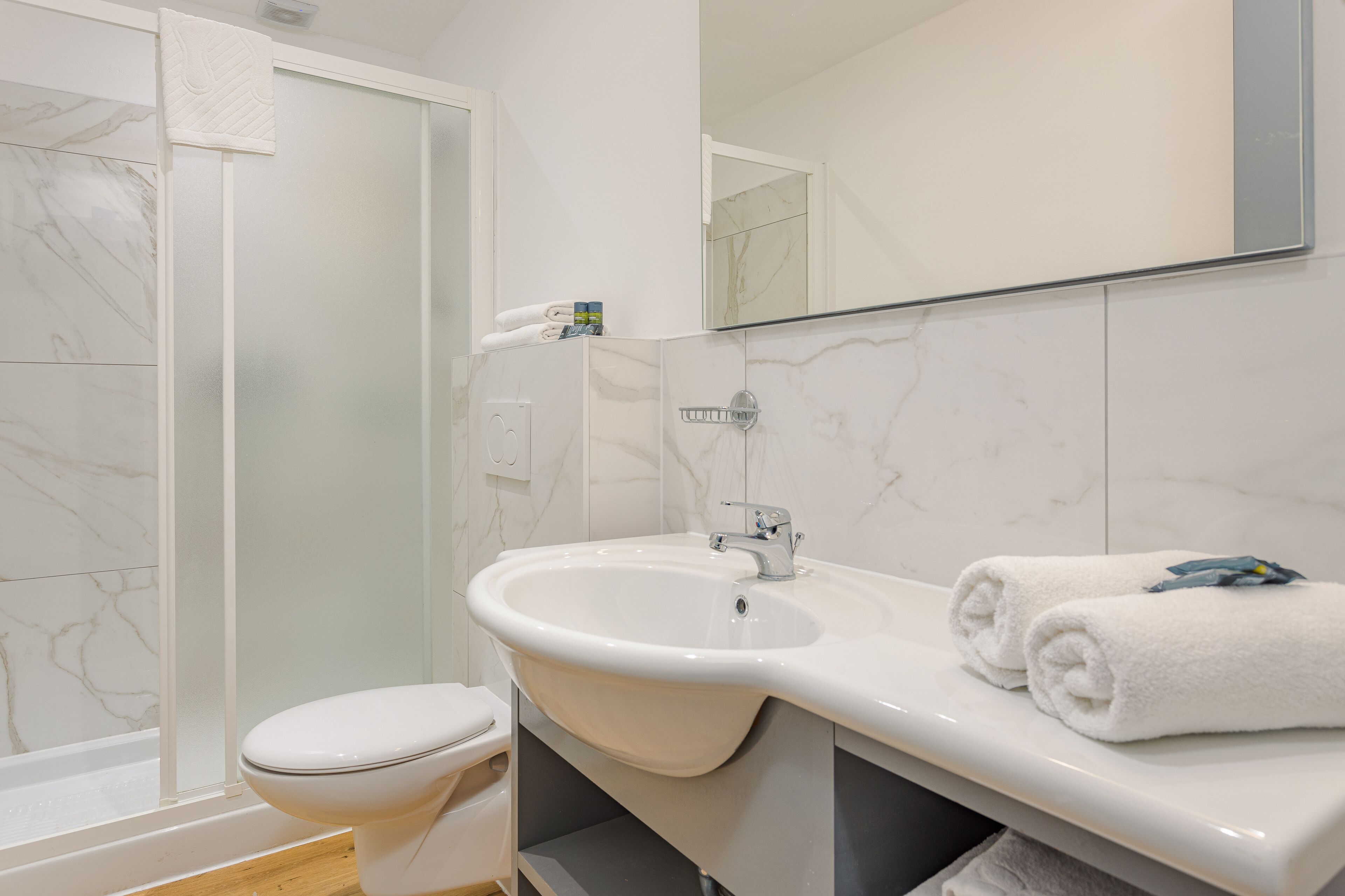 A bathroom with a toilet, sink, and shower.