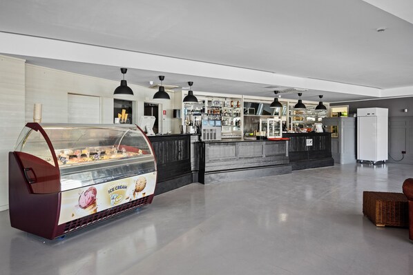 Una heladería moderna con mostrador de autoservicio y una zona de bar con diversas bebidas y aperitivos.