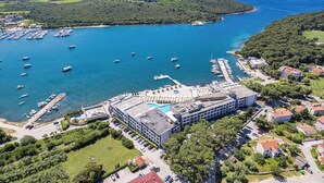 Vista aérea de una zona costera con un puerto deportivo, edificios y una piscina.