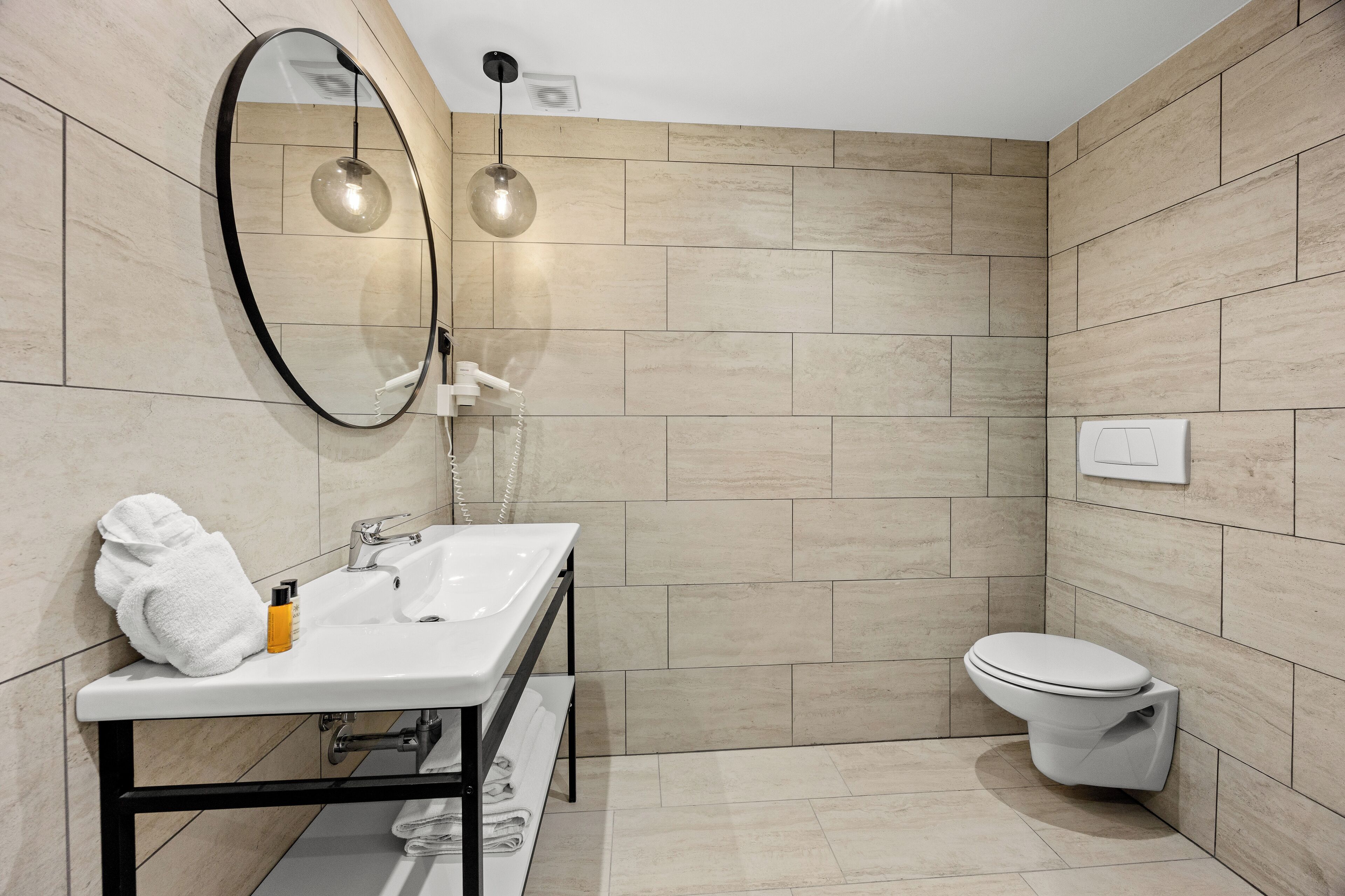 Un baño moderno con un lavamanos blanco, un inodoro y un espejo.