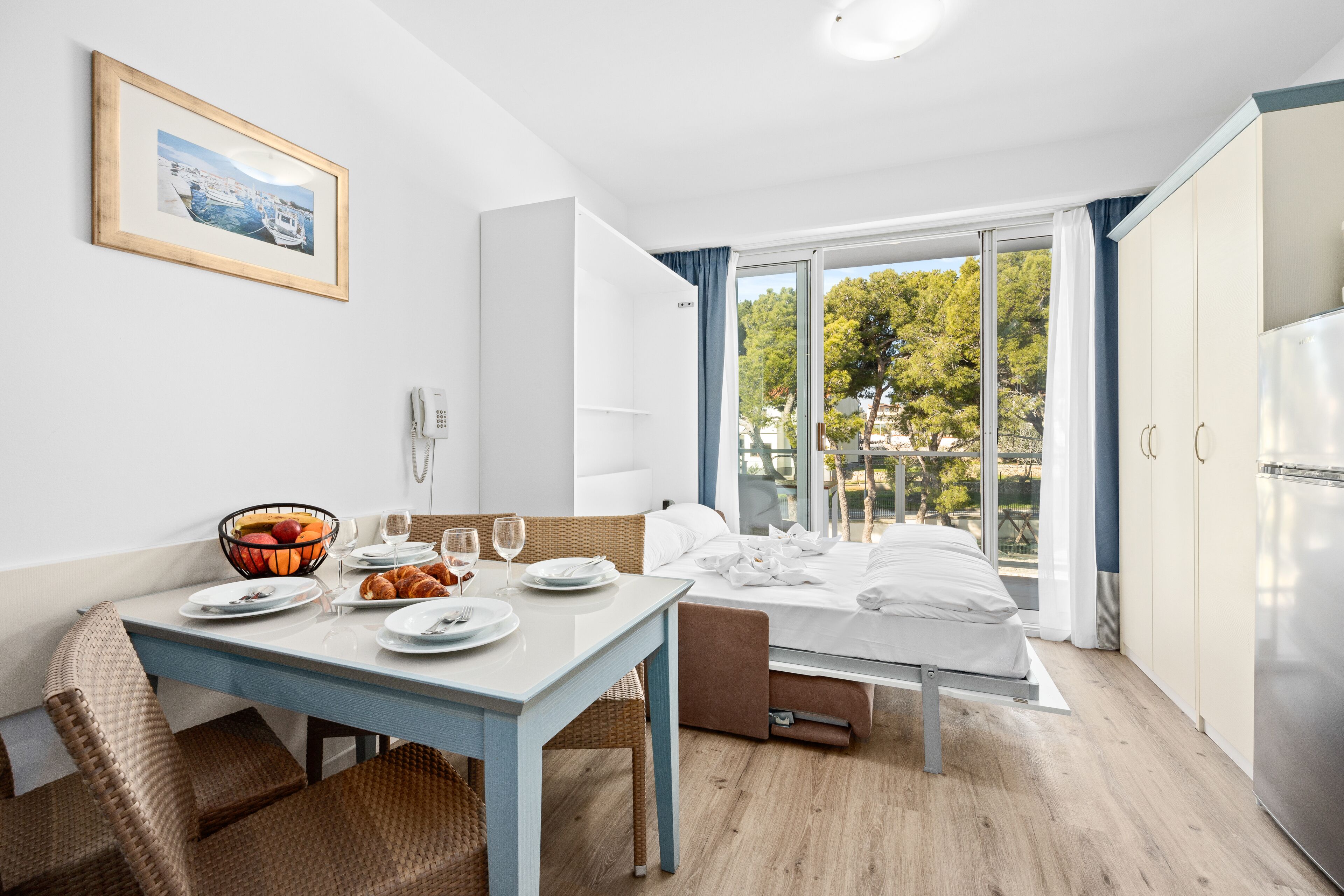 Ein modernes Hotelzimmer mit Essbereich, einem Bett mit Blick und einer Küchenzeile.