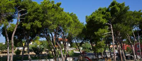 Un parc équipé d’aires de jeux, de murs en pierre et d’arbres.