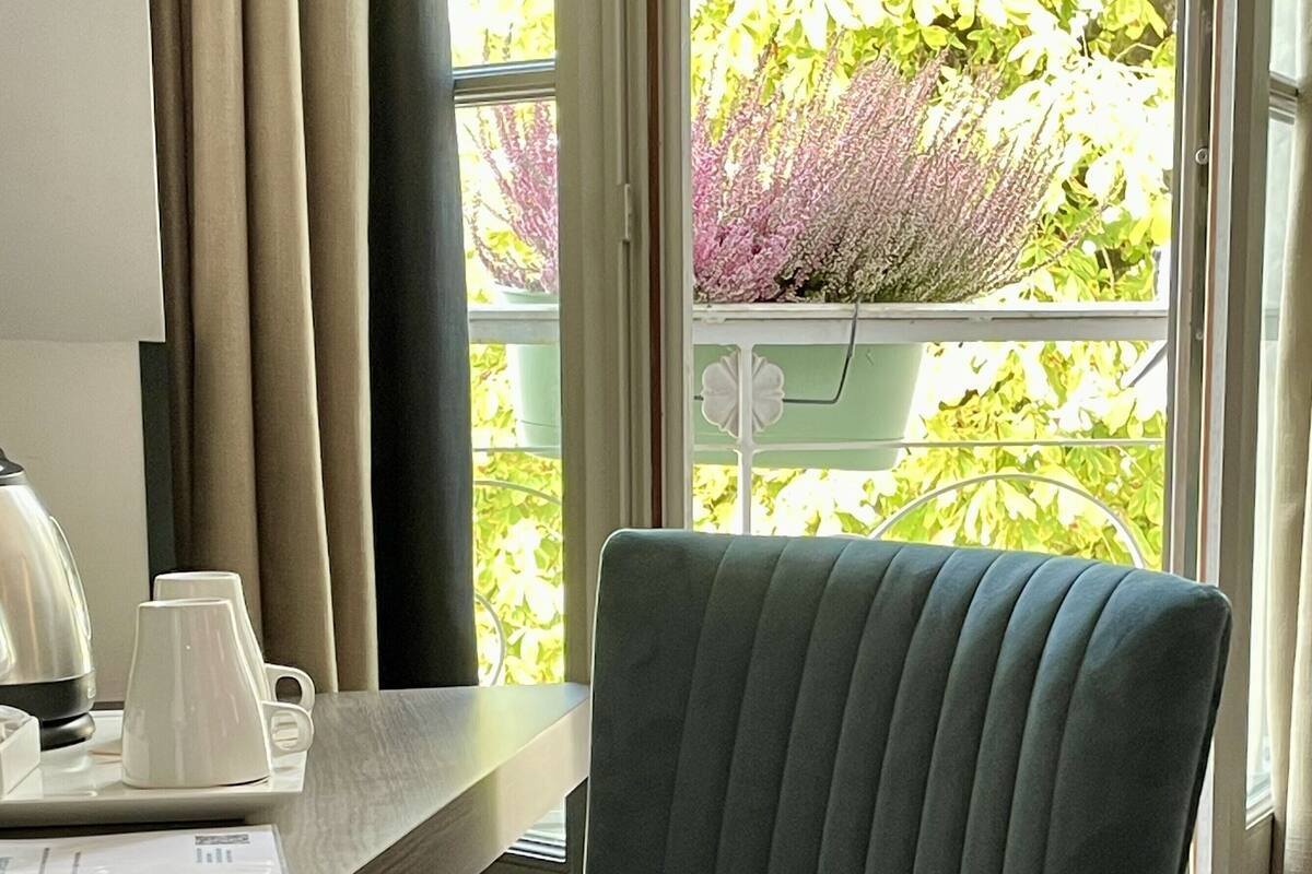 Une chaise dotée d’un haut dossier et d’un siège rembourré, placée près d’une fenêtre donnant sur un paysage verdoyant.