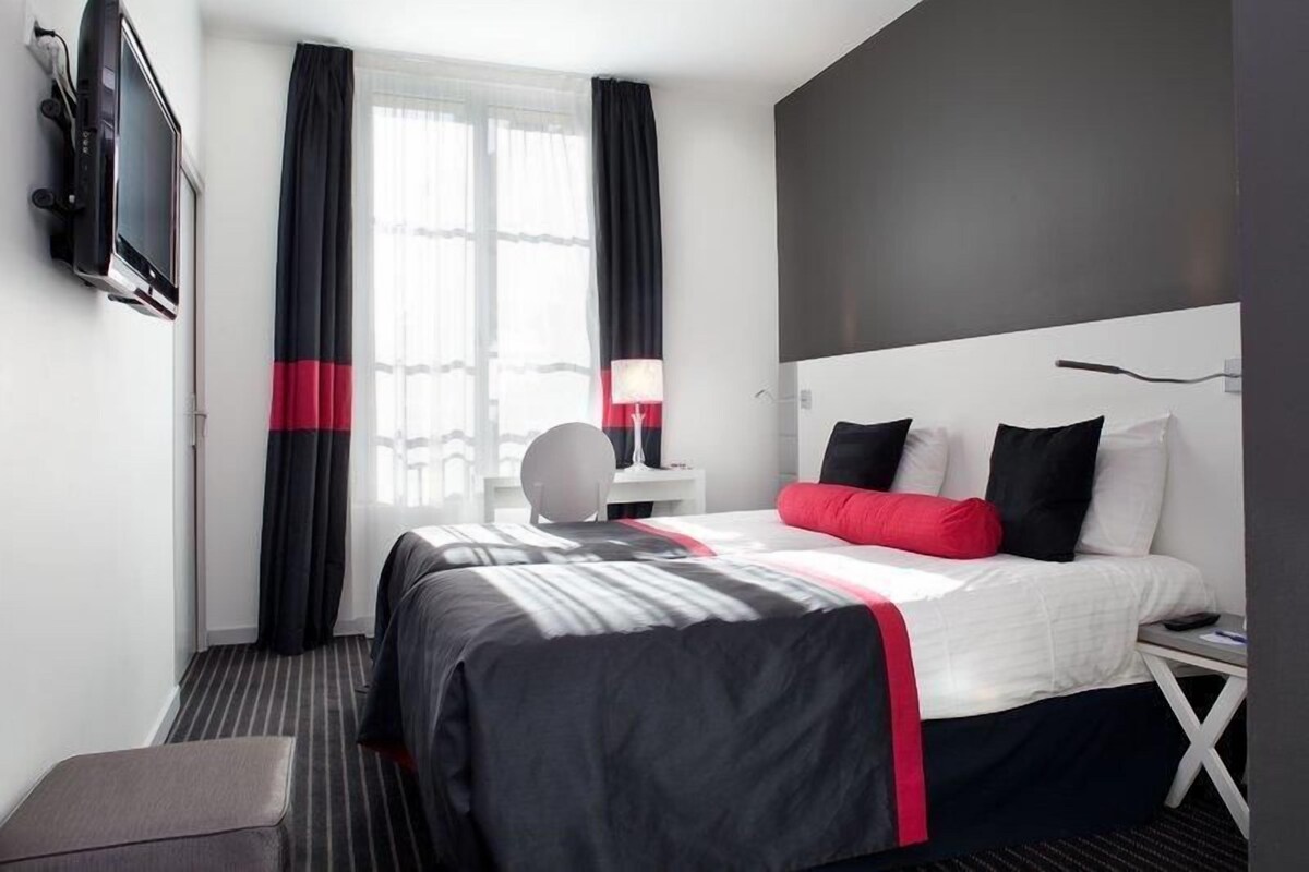 Hotelkamer met een bed, een aan de muur bevestigde televisie, een bureau en een stoel.
