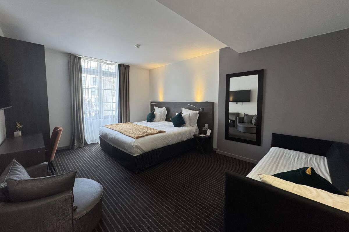 Une chambre d’hôtel moderne équipée d’un grand lit, d’un bureau, d’une chaise et d’un téléviseur.