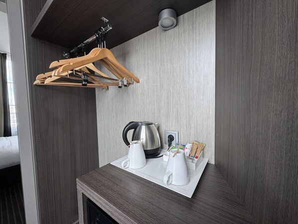 A modern kitchen with a wooden drying rack, a kettle, and a coffee maker on a countertop.