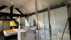 Ein modernes Hotelbad mit einer in Glas gefassten Dusche, einem großen Spiegel und einem Waschtisch mit zwei Waschbecken.