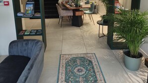 Ein modernes Interieur mit einer Couch, einem Couchtisch, einem Teppich und Regalen mit Büchern und Pflanzen.