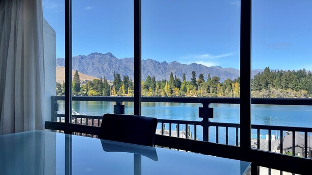 Una habitación con un amplio ventanal que ofrece vistas a un lago y montañas.