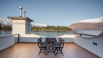 Una terraza con una mesa y bancos, con vistas a un lago y montañas.