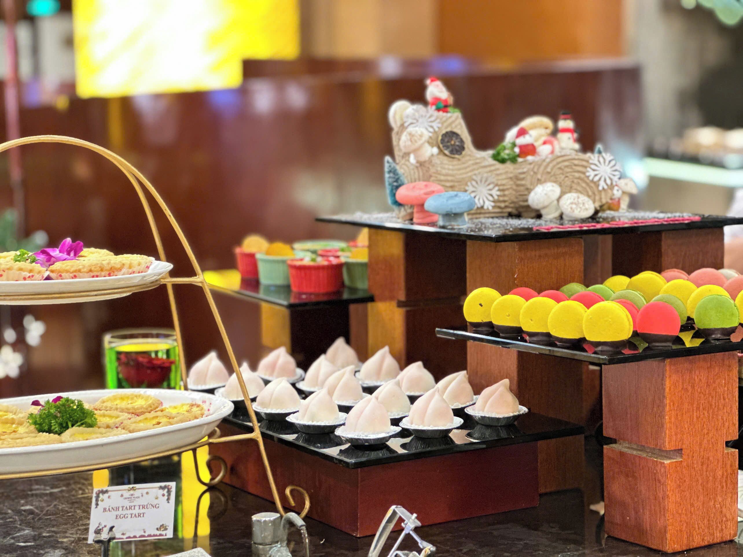 Un buffet proposant une variété de desserts, notamment des tartelettes à la crème et des macarons de différentes couleurs.
